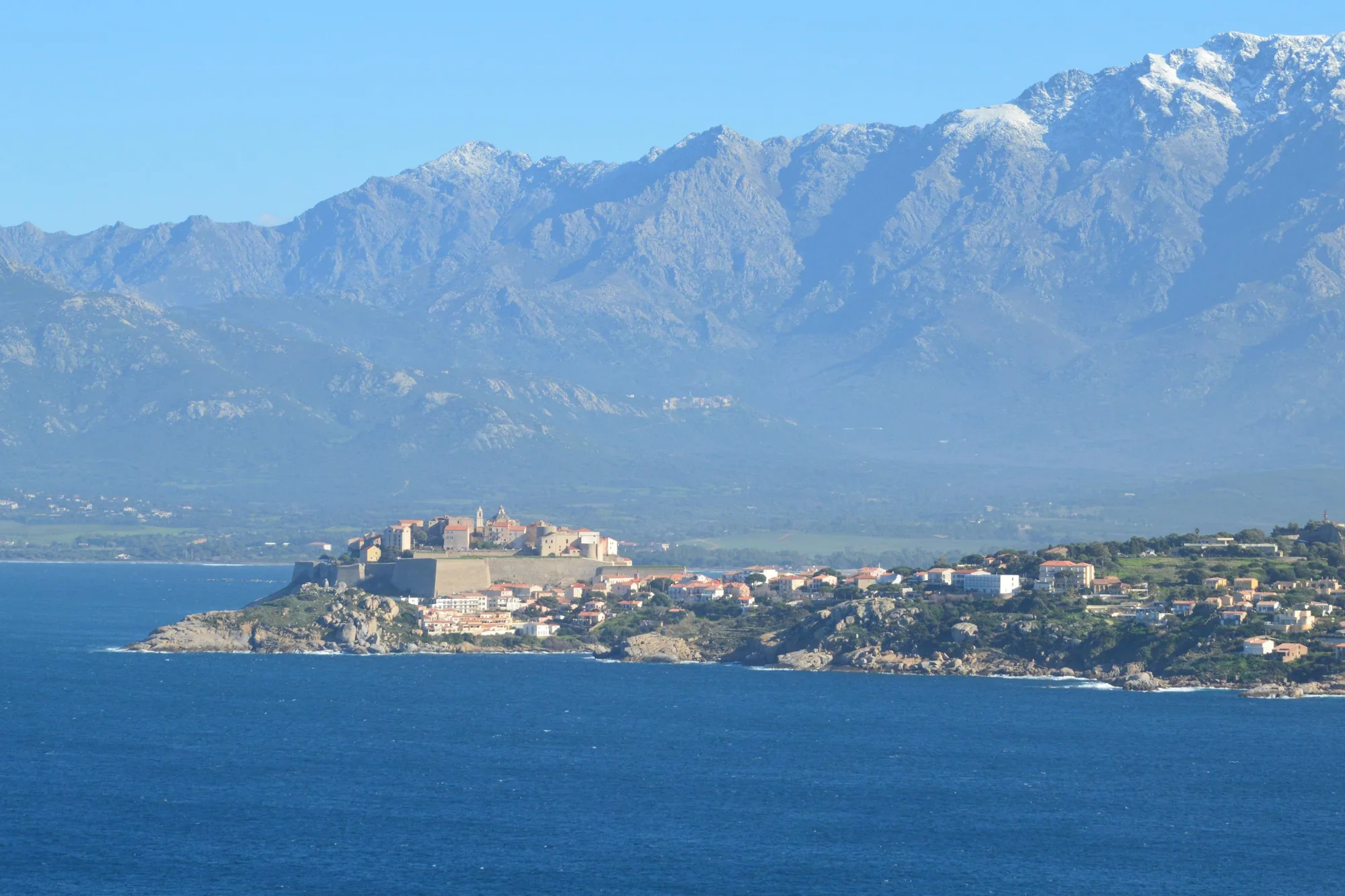 Calvi et sa citadelle au pied des montagnes enneigées
