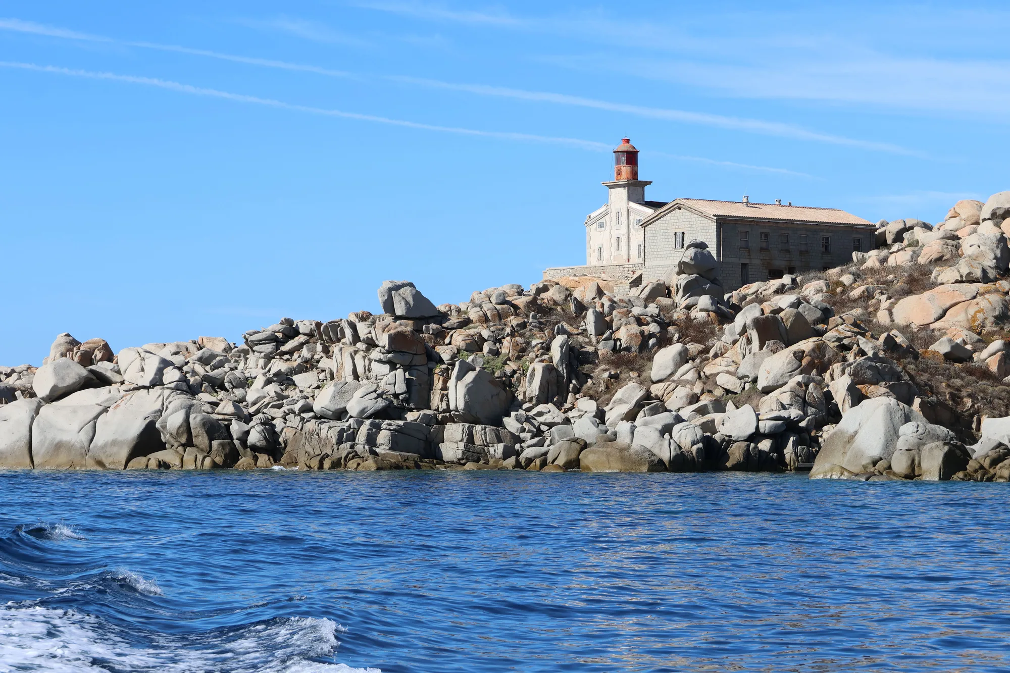 Le phare des Lavezzi au-dessus d’un chaos de blocs de granit, vu depuis la mer