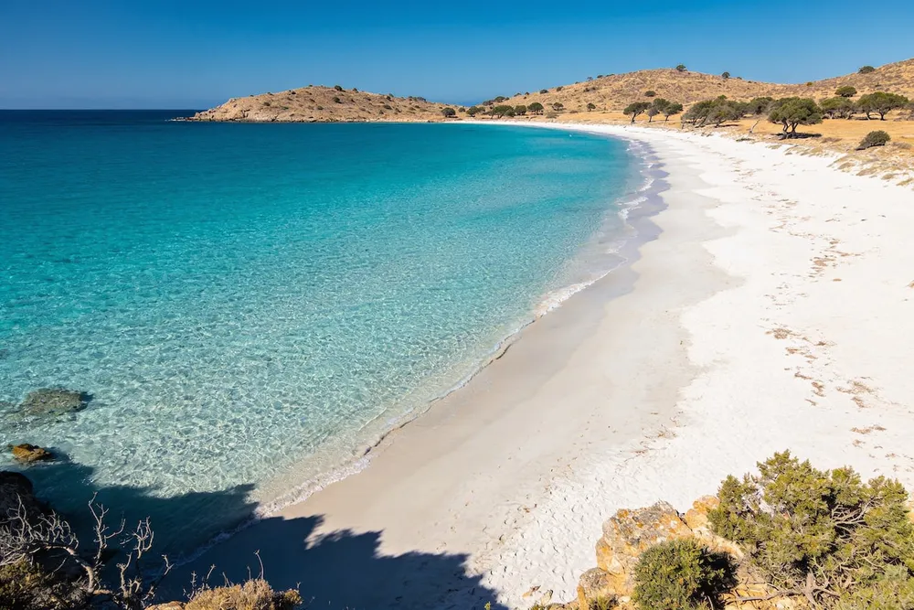 Ilustración de una playa de arena blanca en un paisaje de maquis seco, sin sombra